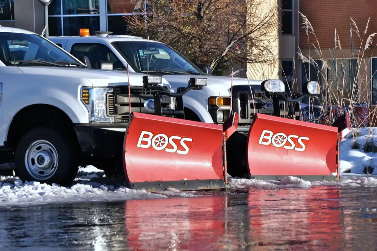 Pickup trucks fitted with snow ploughs lined up before a storm